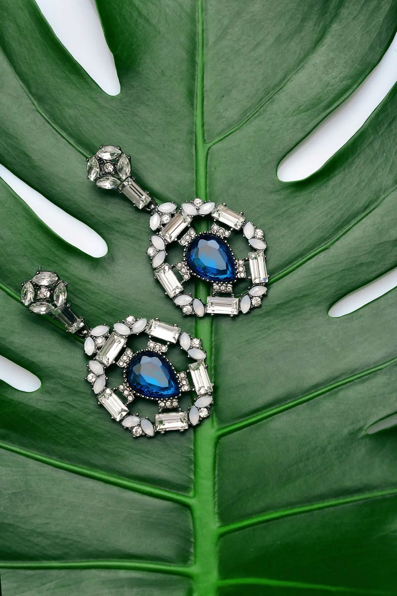 pair of silver-colored earrings with blue gemstone